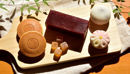 Yokan, monaka, dry sweets, a nerikiri and a daifuku laid out on a wooden board