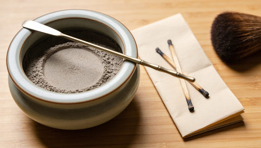 An incense burner with smoothed ash, an ash press, and burnt incense stubs taken out onto paper