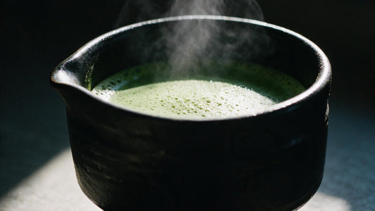 Steam rising from a black tea bowl of freshly whisked matcha in morning light