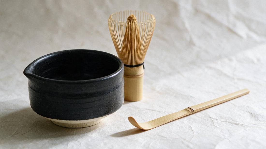 The low, wide Mino-yaki bowl, a Takayama chasen and a flat bamboo chashaku laid out on washi