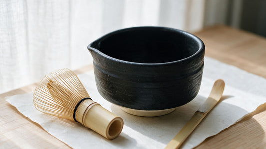 A Takayama chasen beside the low, wide Mino-yaki bowl on washi, shown at true relative size