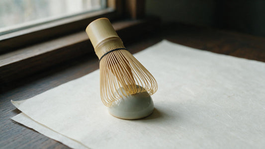 Bamboo matcha whisk resting upside down on a ceramic whisk holder