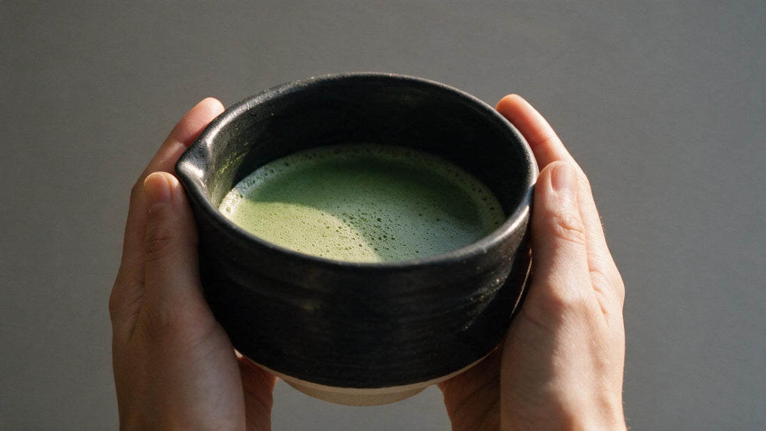 Two hands cradling the low, wide Mino-yaki bowl of whisked thin tea