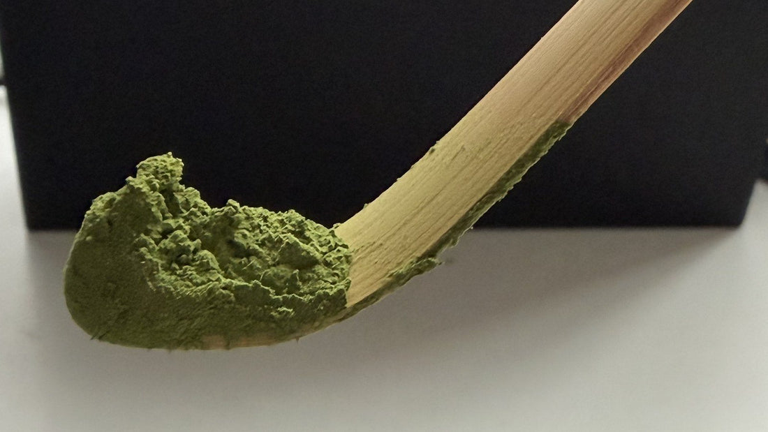 A bamboo tea scoop heaped with matcha powder, seen close up
