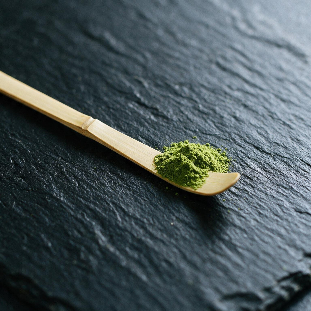 A chashaku holding one scoop of matcha, about one gram; the end is almost flat, so two scoops make a bowl