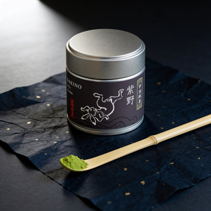 The 30 g tin of Uji matcha "Murasakino" in this set, beside a bamboo scoop (AI-generated image)